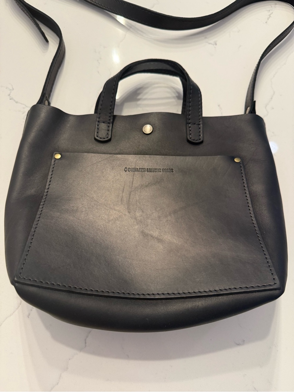 Portland Leather black purse with shoulder strap and handles.